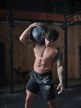 Man lifting heavy ball in the gym