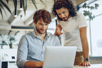 Two young businessmen discussing some ideas in modern office