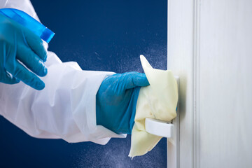 Coronavirus COVID-19 prevention. Man wiping doorknob with antibacterial disinfecting wipe for killing coronavirus.