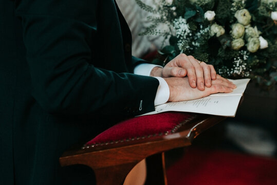 groom in church with focus on hands