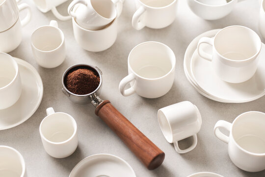 Portafilter with coffee amidst ceramic dishware