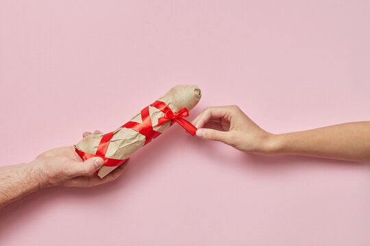 Man's and woman's hands with sex gift wrapped vibrator.