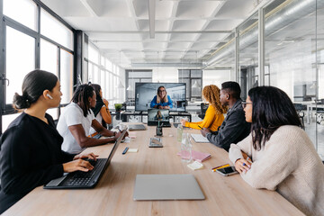 Group of multiracial businesspeople sitting around table having a remote video conference in modern workplace