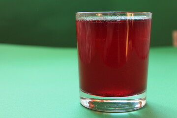 Red drink juice or compote in a glass on a green background with a place for text and copyspace
