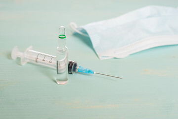 Medical vials,medical mask and syringe isolated on green background, vaccination concept and...