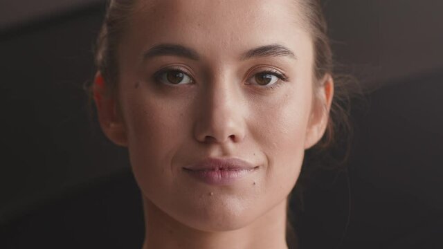 Portrait of young pretty calm woman looking at camera and blinking, slow motion