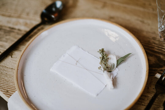 Table set for dinner with empty white card and small flower bouquet on the plates