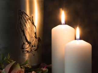 A metal urn with praying hands and burning candles with ashes from a dead person at a funeral. Sad...