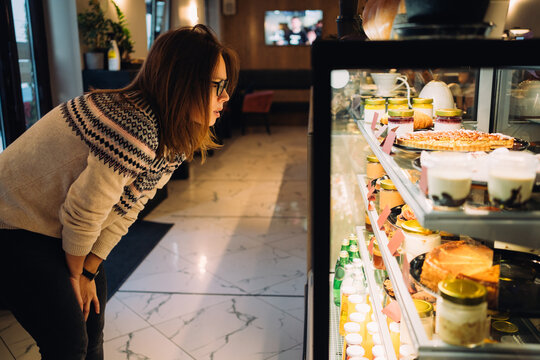 Woman choosing desserts in bakery