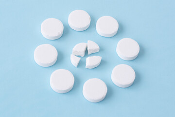 Round white medical pills on a blue background. Health concept