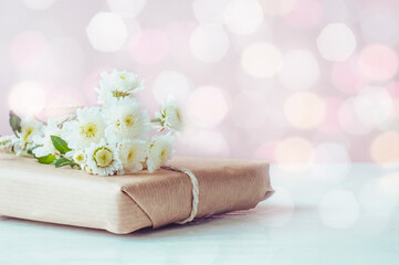 Obraz na płótnie Canvas White chrysanthemums and a gift box on a white wooden background. Spring composition of a gift with bokeh.