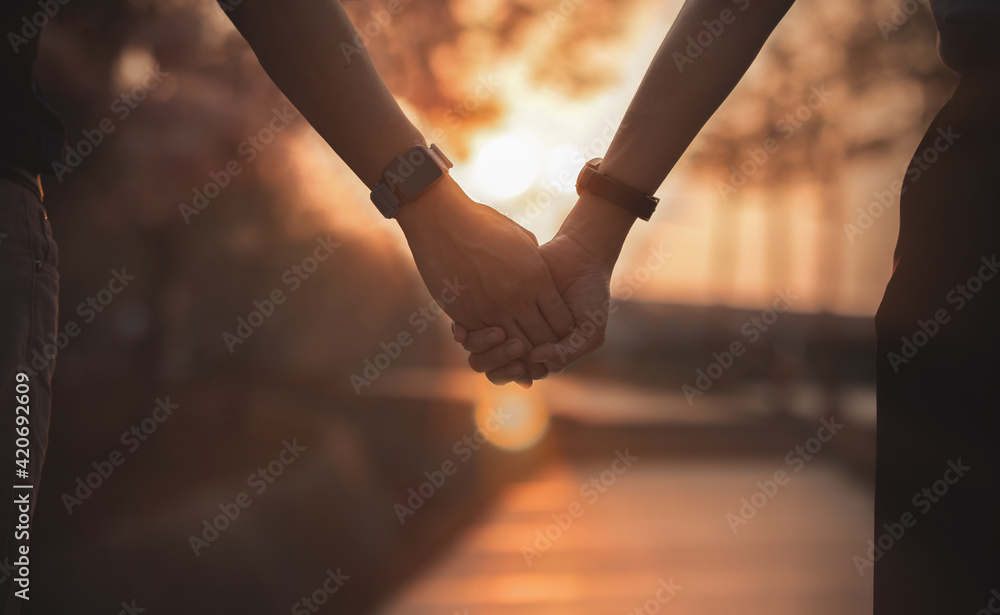 Wall mural Couple hold hands on sunset.