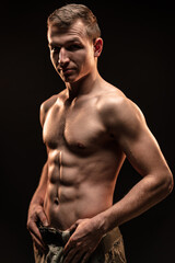 Fototapeta na wymiar Studio shot of muscular topless military man on black background