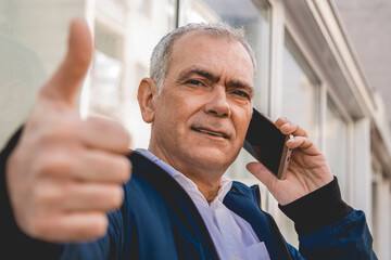 adult man in jacket talking on his phone and doing ok sign with finger
