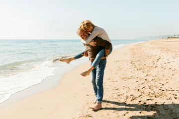 Happy couple piggyback at the beach