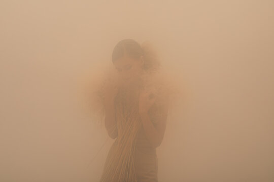 Woman with dry plants in fog