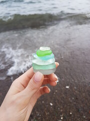 Woman's hand holding transparent stones on blurred sea background