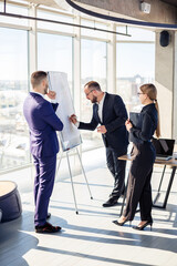 Business professionals. A group of young successful business people are analyzing data using graphs while spending time in a new modern office.