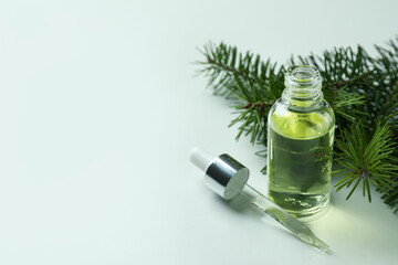 Bottle of pine oil and twig on white background