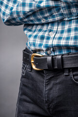 Black leather belt with ash buckle at men's waist close up