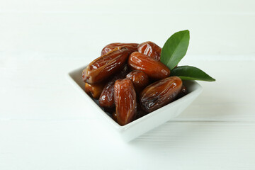 Bowl with dried dates on white wooden table