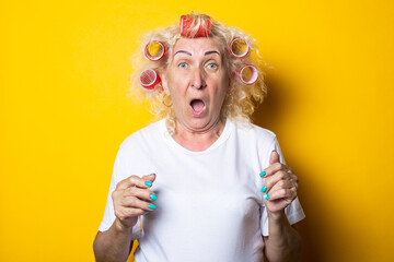 Screaming old woman with curlers in a white T-shirt on a yellow background
