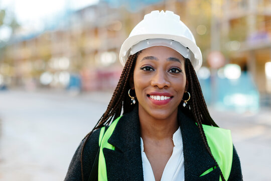 Portrait of attractive black woman wearing protective safety helmet smiling and looking at camera
