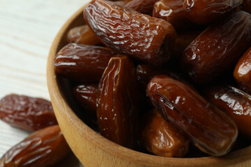 Bowl with dried dates on white wooden table, close up