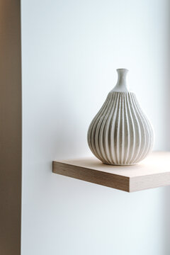 Modern white vase on a wooden shelf