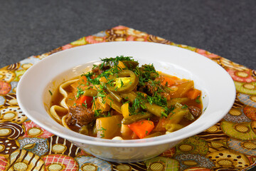 Meat soup with noodles in a plate. Broth on the dining table. 
