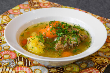 Meat soup with noodles and vegetables in a plate. Asian soup bowl on the dining table.