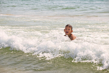 child swims in the sea waves on the beach