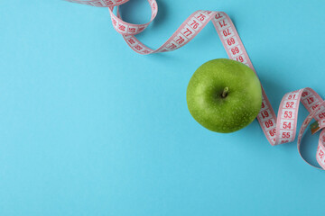 Green apple with measuring tape on blue background