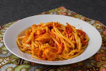 Spaghetti pasta with red sauce and meat. A served platter with food on the dining table.