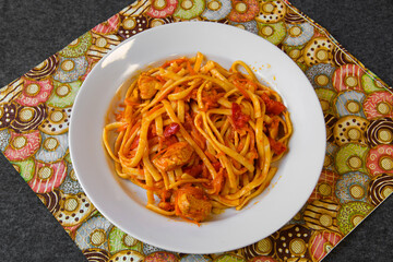 Spaghetti pasta with red sauce and meat. A served platter with food on the dining table.