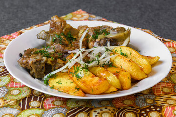 Fried meat with potatoes and vegetables. Hot food on a served platter.