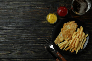 Concept of tasty eating with fried chips and fish, and beer on wooden background