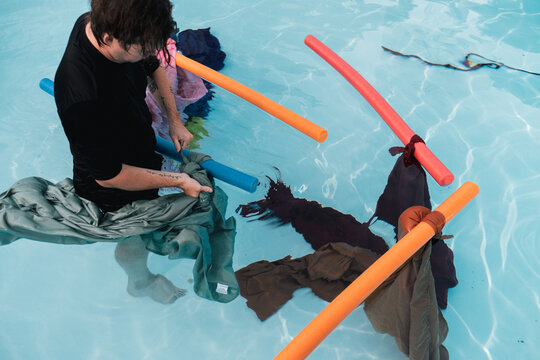 A man prepares multi-colored sheets in a pool for an underwater shoot
