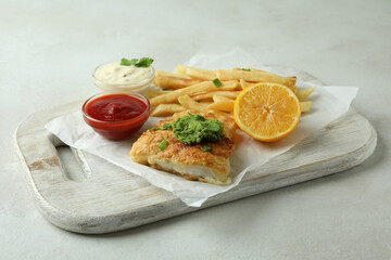 Concept of tasty eating with fried fish and chips on white textured table