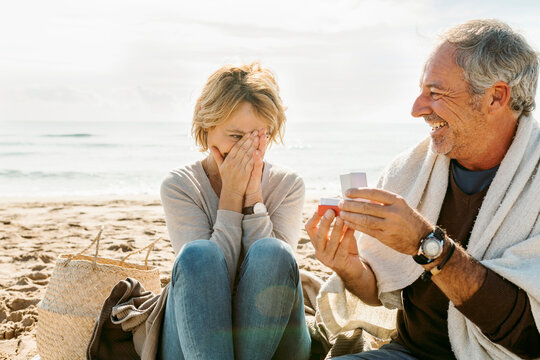 Mature couple propose at the fall beach morning