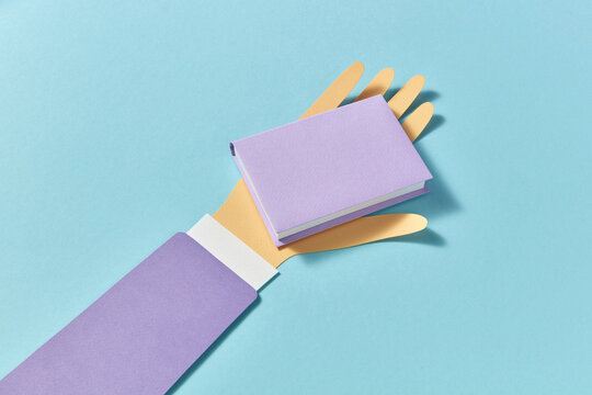 Handmade paper book on a papercraft man's hand.