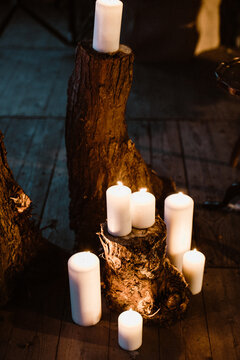 Candles lit indoors and standing on or around tree stumps