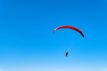 Panoramic photo of two people paraglider in blue sky