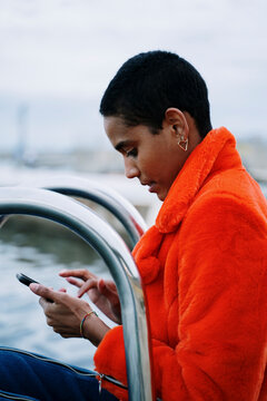 Portrait of a Young trendy woman sitting in pool ladder and texting on her phone during blue hour