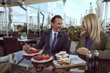 Beautiful couple of travelers enjoying breakfast on a hotel veranda