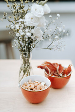 two cups with tapas food and white flowers on a wooden table