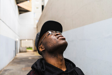 Young urban man looking up to the sky in narrow alley in city