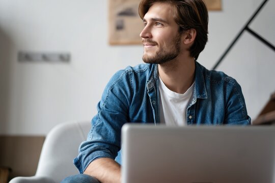 Successful entrepreneur smiling in satisfaction as he checks information on his laptop computer while working