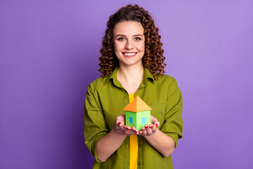 Photo of young cheerful positive smiling girl with curly hair hold little house in hands isolated on purple color background