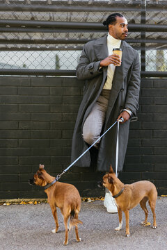 Ethnic guy with dogs enjoying hot drink